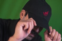 a man wearing a black hat with a red logo on it