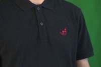 a man wearing a black polo shirt with a red logo on it