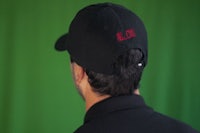 the back of a man wearing a black hat with red lettering
