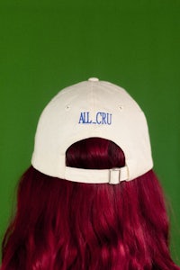 the back of a woman with red hair wearing a hat that says all cru