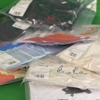 a group of t - shirts in plastic bags on a green background